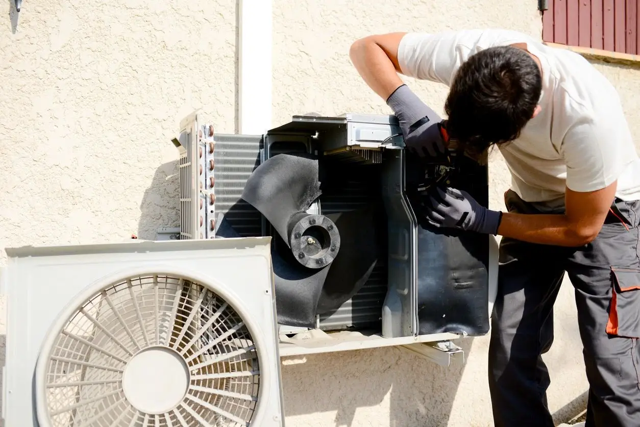 a person working on a broken air conditioner